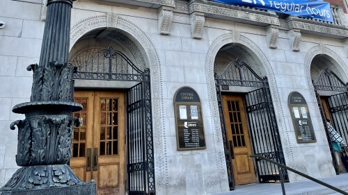 Three stone archways lead to the front doors of a public library.