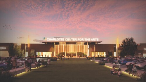 A rendering of a large theater with a lit lobby and long grassy entryway with lit seating.