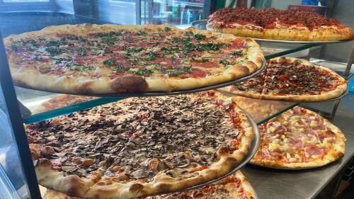 Six large pizzas sit in a glass case.