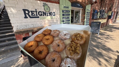 A brick building with the words "Reigning Doughnuts" on the exterior.
