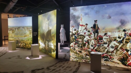A museum interior with three lit panels showing moments in history.