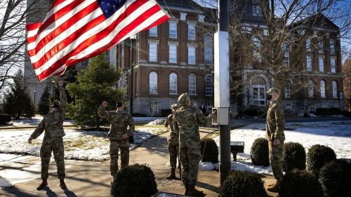 Five people help hang up an American flag.