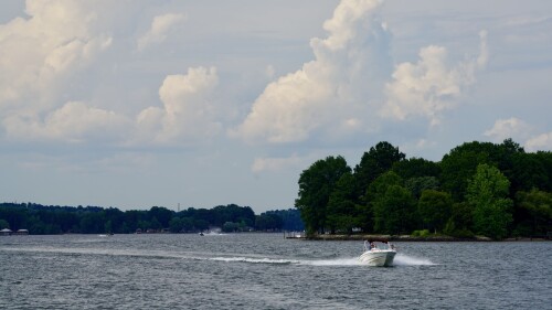 A boat carrying an American flag atop a body of water with a jet ski in the background.