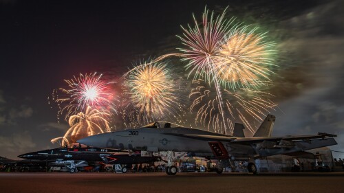 Fireworks explode in the night sky over several parked fighter jets at the SUN 'n FUN Aerospace expo.