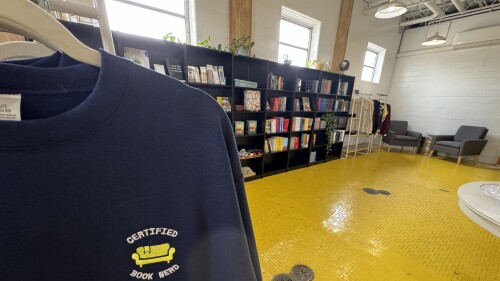 A room of books and a yellow floor with a sweatshirt that reads "Certified Book Nerd."