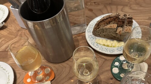 Plates, wine glasses, and a loaf of bread sit on a table at Goodtime Bar.