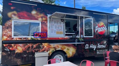 A food truck parked with tables set up outside. 