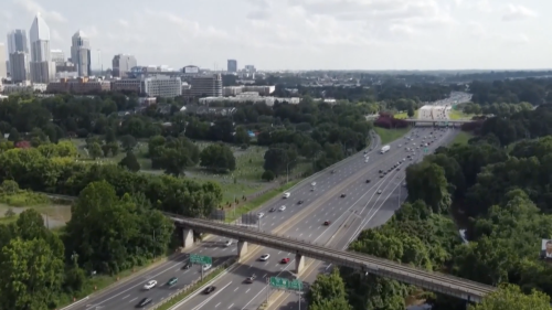 An aerial shot of cars crusing along I-77 with the Uptown skyline in the background.