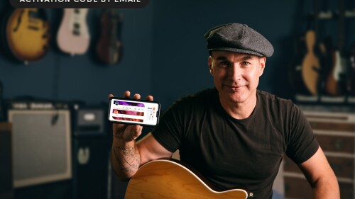 A man with a guitar holds a smartphone. 
