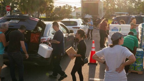 Feeding Tampa Bay volunteers load food and supplies into cars from a massive truck.