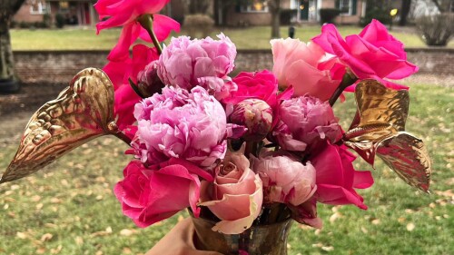 A bouquet of bright pink flowers in a gold vase