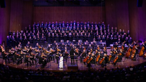The Lexington Philharmonic and Lexington Singers performing onstage together under purple lights.