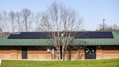 The Tates Creek Community Center, a one story brick building with a green roof. On top of the roof are several large, dark solar panels.