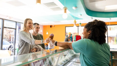 A couple ordering an ice cream cone from an ice cream shop.