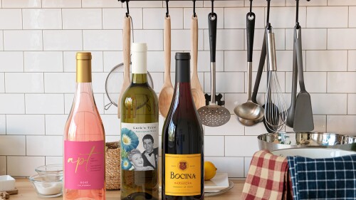 Three bottles of wine on a kitchen counter. 