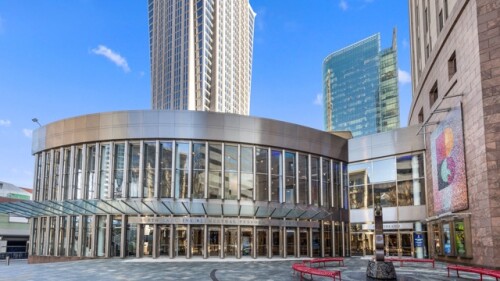An exterior photo of Blumenthal's Belk Theater in Uptown, with a skyscraper in the background.