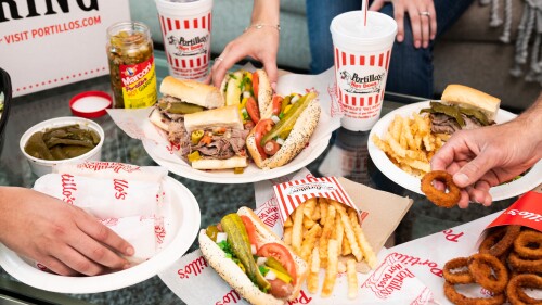 Plates of burgers and hot dogs sit around a table.
