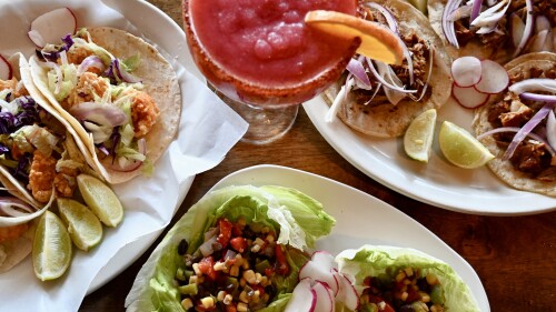 colorful tacos sit on a plate next to a red drink