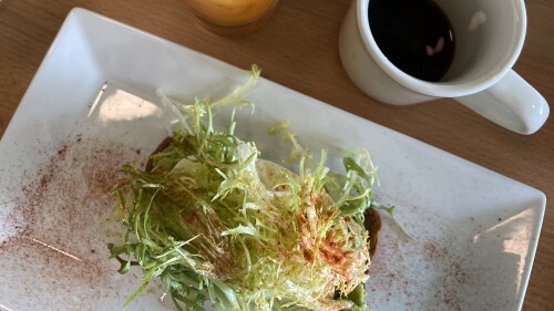 Two plates featuring avocado toast with lettuce + paprika with a coffee mug and orange juice from Beau's Cafe.