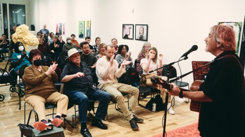 The audience is clapping along to a person singing into a microphone.
