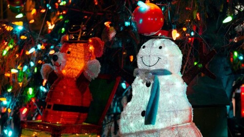 A close up of holiday ornaments on a tree