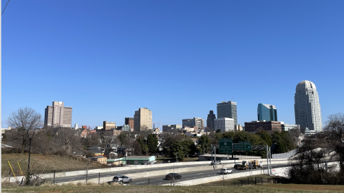 Clear blue sky with Winston-Salem skyline and four-lane highway down below.