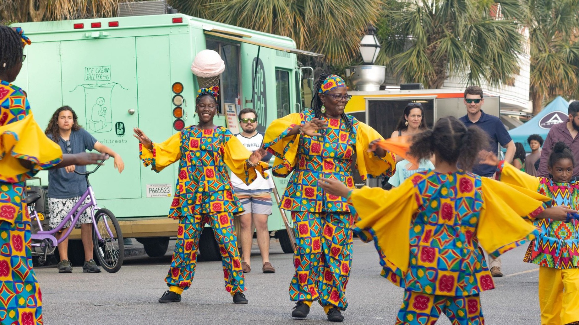 on lookers watch performers in yellow, blue, and red outfits 